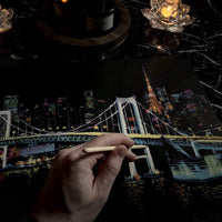 Nattvy Tokyo – hand med träverktyg skrapar vid Rainbow Bridge, Tokyo Tower i bakgrunden